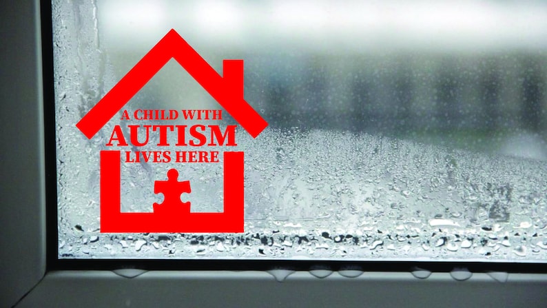 May include: A red house-shaped sticker on a window with condensation. The sticker says "A child with autism lives here" and has a jigsaw piece inside.