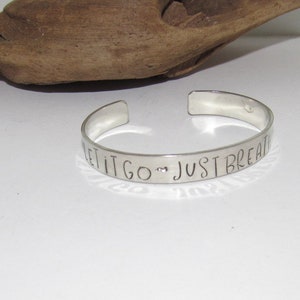 May include: Silver bracelet with the words "Let it go, Just Breathe" engraved on it.