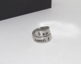 May include: A silver ring with the words "I am enough!" engraved on it.