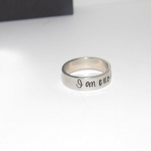 May include: A silver ring with the inscription "I am enough" engraved on the band.
