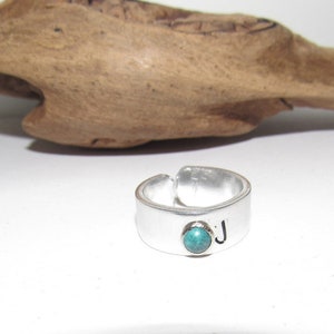 May include: A silver adjustable ring with a turquoise stone and the letter "J" engraved on the band.