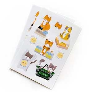 Op de afbeelding: Een vel stickers met schattige cartoonkatten in verschillende poses. De stickers hebben een witte achtergrond met een gele zon en de tekst "Have a nice day".