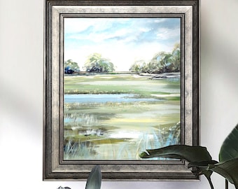 May include: A framed landscape painting with a silver-toned frame. The artwork depicts a marsh scene with green and yellow grasses, blue water, and a cloudy sky. The painting is displayed on a white wall.