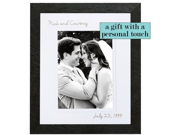 May include: Black and white photo of a couple in a black frame. The photo shows a bride and groom embracing. The text "Nick and Courtney" is written above the photo and "July 23, 1999" is written below the photo. The text "a gift with a personal touch" is written in a light blue box in the upper right corner of the image.