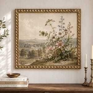 May include: A square landscape painting in a decorative gold frame featuring a bouquet of wildflowers in the foreground and a rolling countryside with trees and distant mountains in the background, rendered in muted earth tones and soft blue hues.