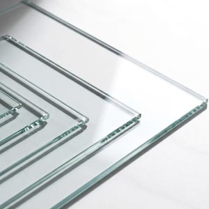 May include: A collection of clear glass panels of varying sizes, arranged in a layered composition. The edges of the glass are visible, reflecting light and creating subtle shadows. The overall effect is clean and minimalist.