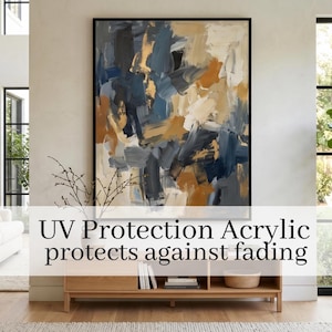 May include: Large abstract painting in a black frame, featuring brushstrokes of blue, gold, and white. The artwork hangs above a wooden cabinet. Text on the image reads: UV Protection Acrylic protects against fading.