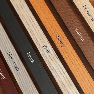 Puede incluir: Primer plano de ocho muestras de madera en diferentes colores y acabados, incluyendo caoba, lavado azul, negro, gris, miel, nogal y blanco lavado marr&oacute;n.