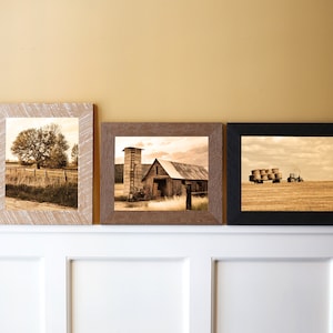May include: Three framed sepia-toned photographs of rural scenes. The leftmost photo shows a tree in a field. The middle photo shows a barn with a silo. The rightmost photo shows a tractor pulling a wagon full of hay bales.