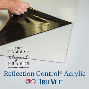 May include: A sheet of Reflection Control&reg; Acrylic by Tru Vue is shown with a protective film being peeled back. The acrylic sheet is white, and the protective film is black. The text "Tammy's Elegant Frames" is also visible.