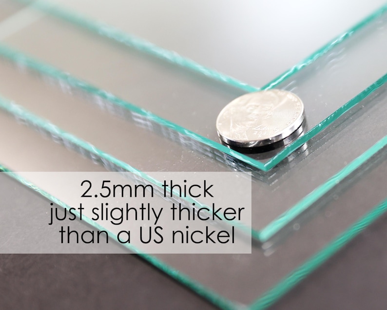 May include: Close-up of clear glass sheets, 2.5mm thick, with a US nickel for scale. The text reads: "2.5mm thick just slightly thicker than a US nickel."