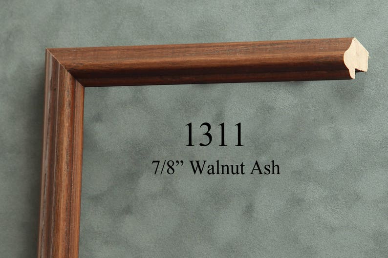 May include: A close-up of a brown wood picture frame with a beveled edge. The frame is 7/8" wide and is made of walnut ash. The frame is labeled with the number 1311.