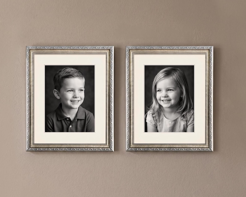 Op de afbeelding: Twee ingelijste zwart-wit portretten van kinderen. Elk portret zit in een zilveren sierlijke lijst met een cr&egrave;mekleurige passe-partout. De portretten zijn van een lachende jongen en een lachend meisje.