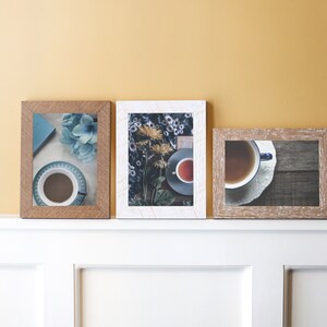 May include: Three framed pictures with different images. The first picture is a close-up of a blue flower and a cup of coffee. The second picture is a close-up of a cup of tea and a bouquet of yellow flowers. The third picture is a close-up of a cup of tea on a wooden surface.