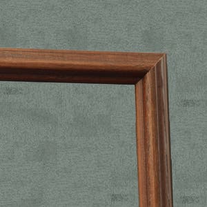 May include: Close-up of the corner of a dark brown wooden picture frame.