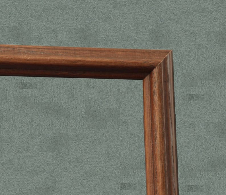 May include: Close-up of the corner of a dark brown wooden picture frame.
