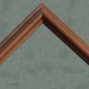 May include: A close-up of a wooden picture frame with a dark brown finish. The frame has a simple, classic design with a slightly raised edge.
