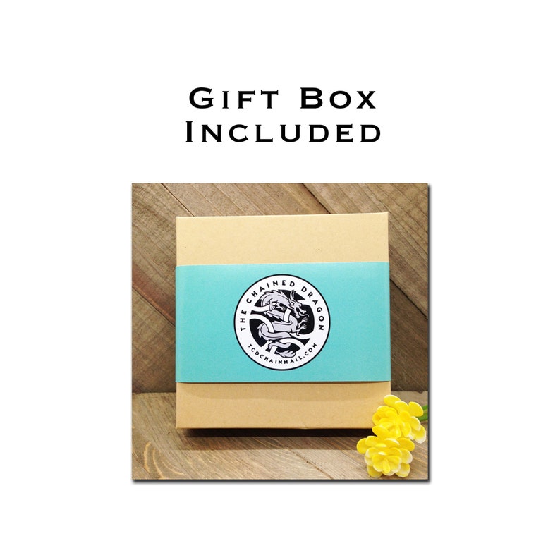 May include: A brown gift box with a blue ribbon and a logo that says "The Chained Dragon" on it. The box is sitting on a wooden surface.