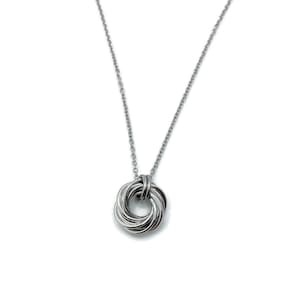 May include: A silver necklace with a circular pendant made of multiple intertwined strands of metal.