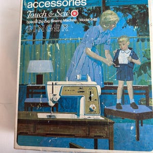 May include: A vintage Singer Touch & Sew Special Zig-Zag Sewing Machine Model 648 accessories box. The box features a blue-toned illustration of a person adjusting a child's clothing, with the text accessories, Touch & Sew, and SINGER.