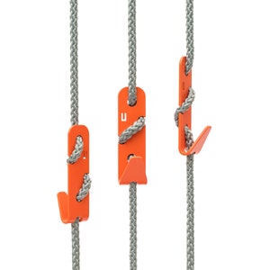 Könnte beinhalten: Drei orangefarbene Seilhaken mit einem grauen Seil, das an jedem hängt. Die Haken sind U-förmig mit einem kleinen Haken unten.