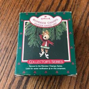 May include: A green and red Hallmark box featuring a reindeer in a red jacket and green skirt ice skating. The box reads "REINDEER CHAMPS DANCER-DATED 1987" and "COLLECTOR'S SERIES".