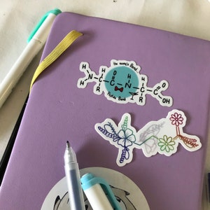May include: A purple notebook with a sticker of a chemical structure with the text "the name's Bond..." and "Peptide Bond". The sticker is surrounded by colorful flower stickers.