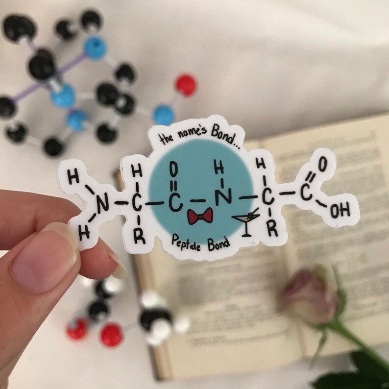 May include: A white sticker with a blue circle and a chemical formula for a peptide bond. The text "the name's Bond..." is above the circle and "Peptide Bond" is below the circle. The circle has a red bow tie and a martini glass.
