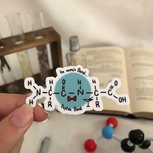 May include: A blue and white sticker with a cartoon illustration of a peptide bond. The text "the name's Bond..." and "Peptide Bond" are written on the sticker.