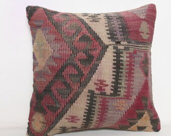 May include: A square throw pillow with a geometric pattern in shades of red, black, and beige. The pillow is made of woven fabric and has a traditional Turkish kilim design.