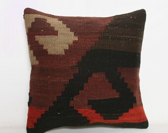May include: A brown, black, and red patterned throw pillow with a geometric design. The pillow is made of woven fabric and has a square shape.