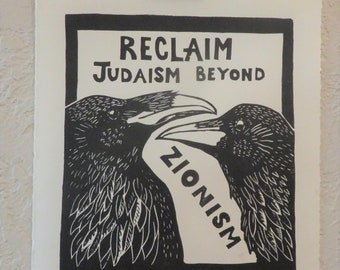 May include: Black and white print featuring two ravens with the text "RECLAIM JUDAISM BEYOND ZIONISM." The ravens are facing each other, with a banner between their beaks. The print is held by a binder clip.