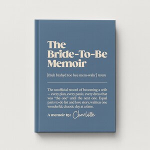 May include: A blue hardcover book titled The Bride-To-Be Memoir with cream-colored text. The cover features a phonetic pronunciation guide, a definition of the title, and the text A memoir by: Charlotte in a script font at the bottom.