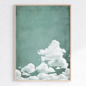May include: A framed print of a teal blue sky with white clouds. The clouds are clustered together in the bottom right corner of the image.