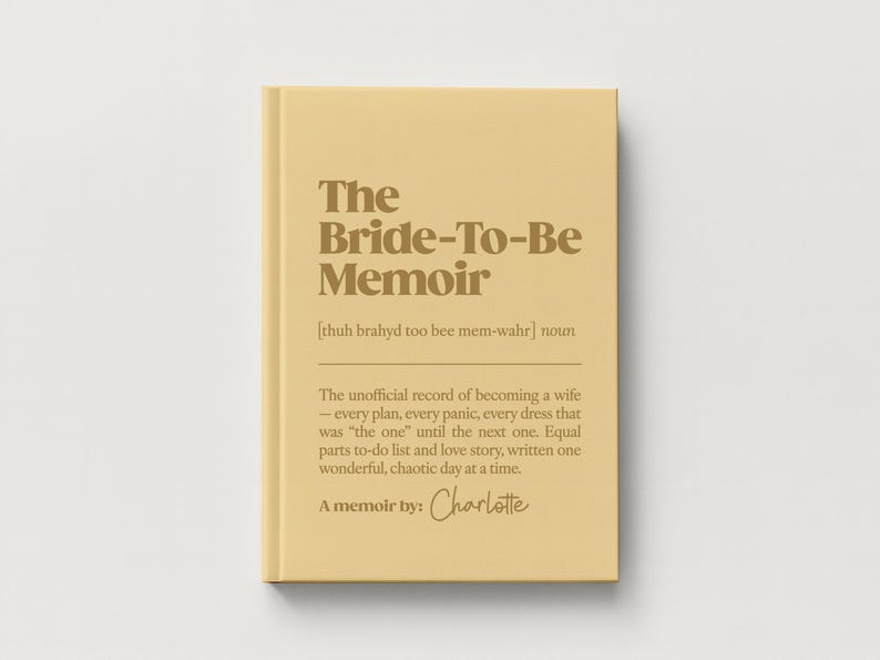 May include: A hardcover book with a light yellow cover and dark brown text. The title reads The Bride-To-Be Memoir, followed by a phonetic pronunciation, a definition of the term, and the text A memoir by: Charlotte in a script font.