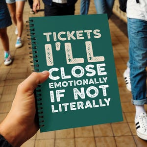 May include: A dark green spiral-bound notebook featuring the white text TICKETS I'LL CLOSE EMOTIONALLY IF NOT LITERALLY printed on the front cover. The notebook has a black metal wire binding along the left side and a matte finish on the cover.