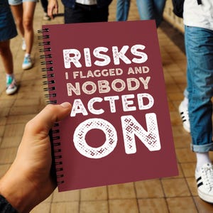 Pode incluir: Um caderno de espiral cor de vinho com texto branco que diz: RISKS I FLAGGED AND NOBODY ACTED ON. A capa tem uma aparência texturizada e as letras são preenchidas com um pequeno padrão geométrico repetitivo. O caderno é segurado na mão.