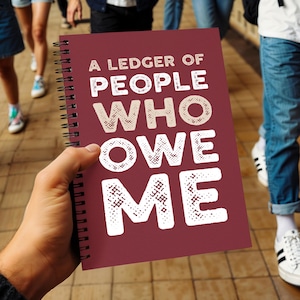 May include: A spiral-bound notebook with a dark red cover featuring the white text A LEDGER OF PEOPLE WHO OWE ME. The notebook has a black metal coil binding along the left side and a matte finish on the front cover with bold, block lettering.