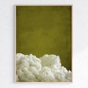 May include: A framed abstract art print featuring a white cloud-like shape against a solid olive green background.