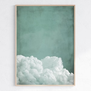 May include: A framed print of a white cloud against a teal blue background. The cloud is fluffy and appears to be floating in the sky.