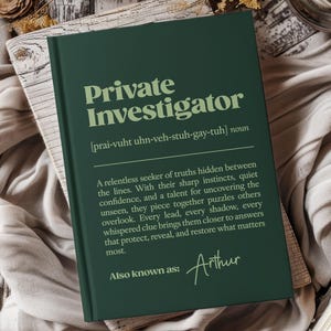 Puede incluir: Un libro verde oscuro titulado "Private Investigator" con una definición y el nombre "Arthur". El libro está sobre una superficie de madera con una tela suave de color neutro. El texto describe la profesión.