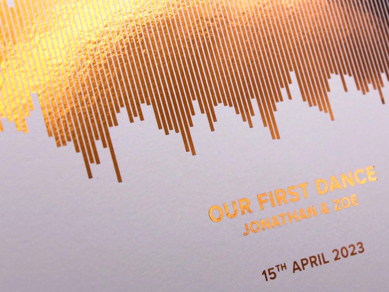 May include: A wedding keepsake with gold foil details. The design features a soundwave pattern with the text "OUR FIRST DANCE" and the names "JONATHAN & ZOE" along with the date "15TH APRIL 2023" in gold foil.