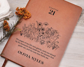 Może przedstawiać: Brązowy skórzany dziennik z tekstem "CHAPTER 21" i wzorem kwiatowym. Cytat "The pages of my life turn gently, each one kissed by the moments that made me, the dreams that guide me, and the love that holds me." jest nadrukowany na okładce. Imię "OLIVIA NYLES" również jest nadrukowane na okładce.