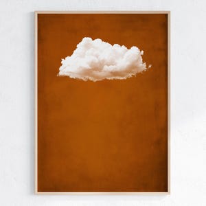 Op de afbeelding: Een enkele witte wolk tegen een effen oranje achtergrond. De wolk bevindt zich in het bovenste midden van de afbeelding.