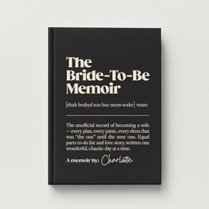 May include: A black hardcover book titled The Bride-To-Be Memoir with white text. The cover features a phonetic pronunciation guide, the noun classification, and a descriptive paragraph about wedding planning, ending with the handwritten name Charlotte.