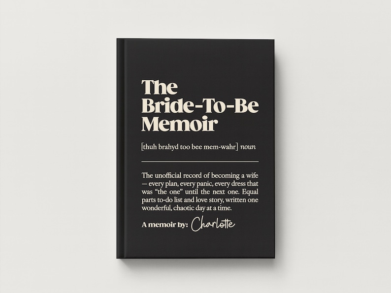May include: A black hardcover book titled The Bride-To-Be Memoir with white text. The cover features a phonetic pronunciation guide, the noun classification, and a descriptive paragraph about wedding planning, ending with the handwritten name Charlotte.