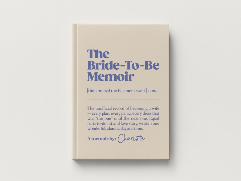 May include: A beige hardcover book titled The Bride-To-Be Memoir in blue text. The cover includes a phonetic pronunciation, the noun definition, and a description of the content as an unofficial record of becoming a wife, signed by Charlotte.