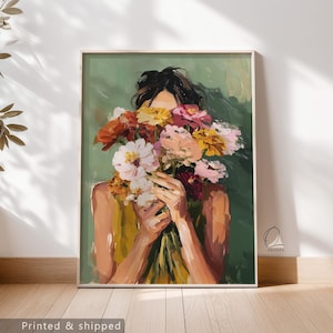 May include: An art print depicting a person with a bouquet of flowers, obscuring the face. The artwork uses yellows, oranges, pinks, and whites against a green backdrop. The print is framed and ready to hang, a decorative piece for any room.
