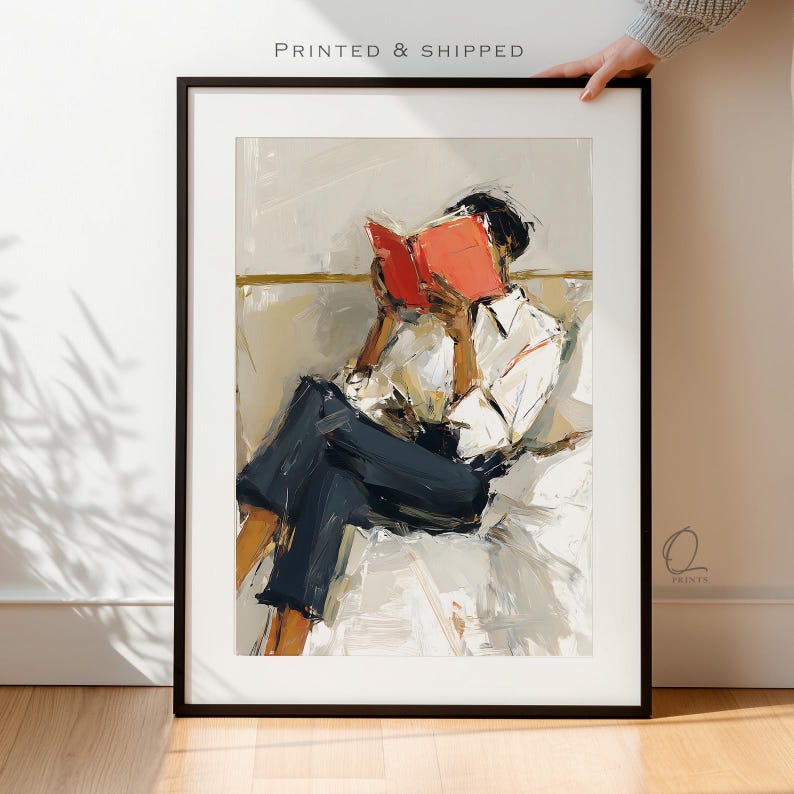 May include: Framed art print featuring an abstract painting of a person reading a book. The person is wearing a white shirt and dark blue pants. The book is bright red. The text "PRINTED & SHIPPED" is at the top.