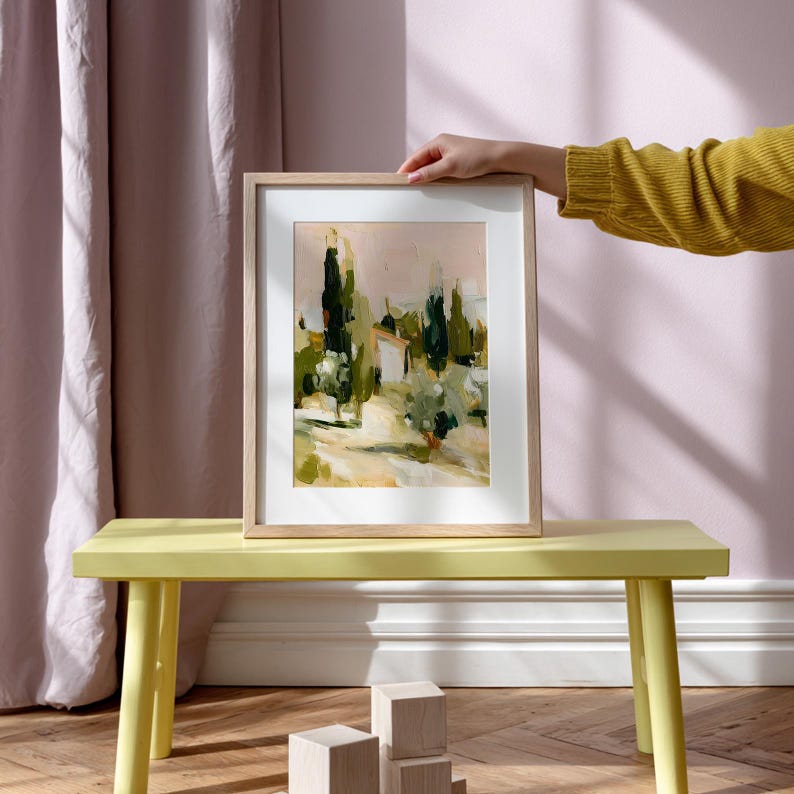 Puede incluir: Una l&aacute;mina art&iacute;stica enmarcada que presenta un paisaje impresionista con altos cipreses de color verde oscuro, follaje verde oliva y un fondo beige claro. La obra est&aacute; dentro de un marco de madera clara con un borde de paspart&uacute; blanco.